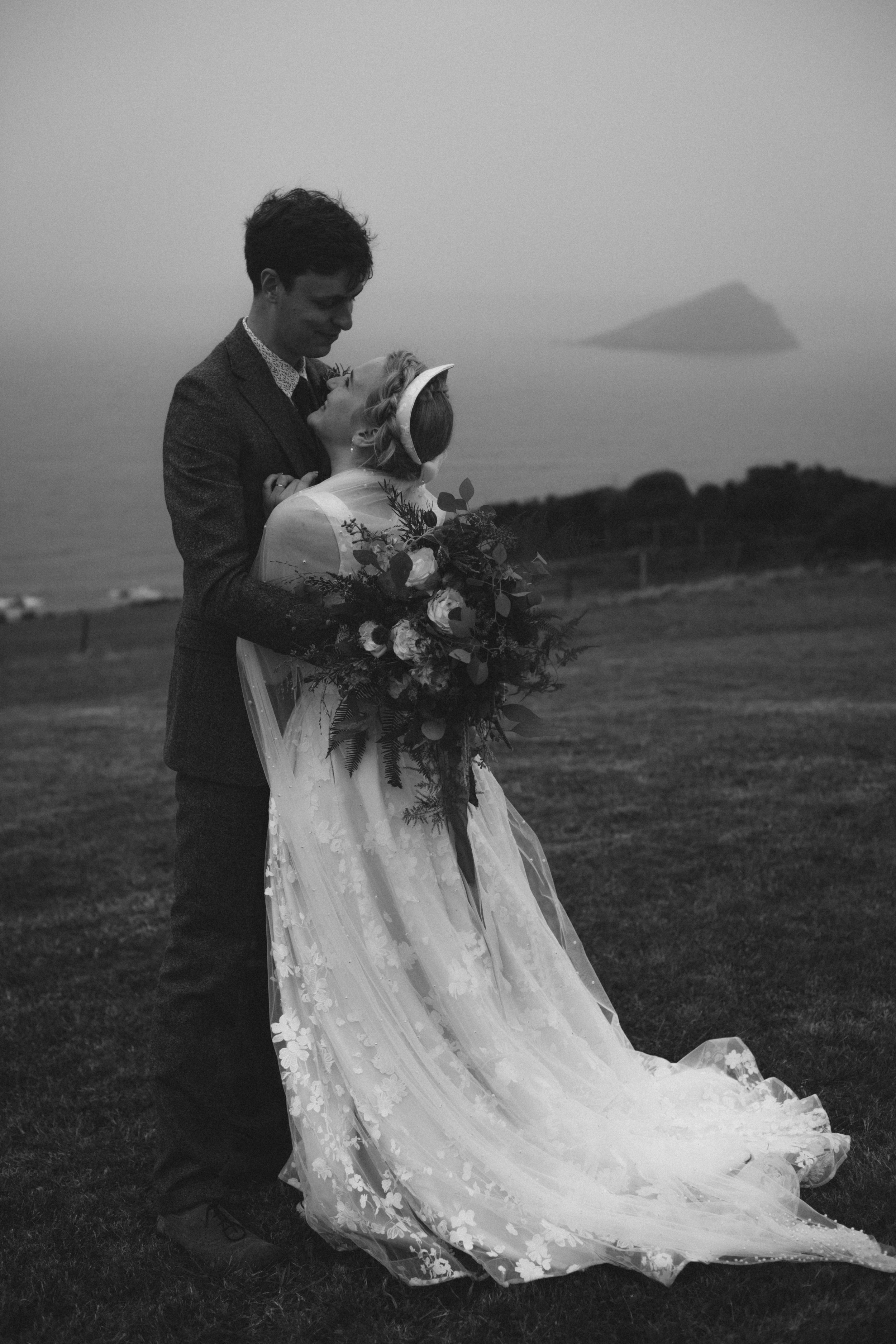 deeply romantic and atmospheric couple portraits in black and white on the cliff tops of devon with wembury island in the background