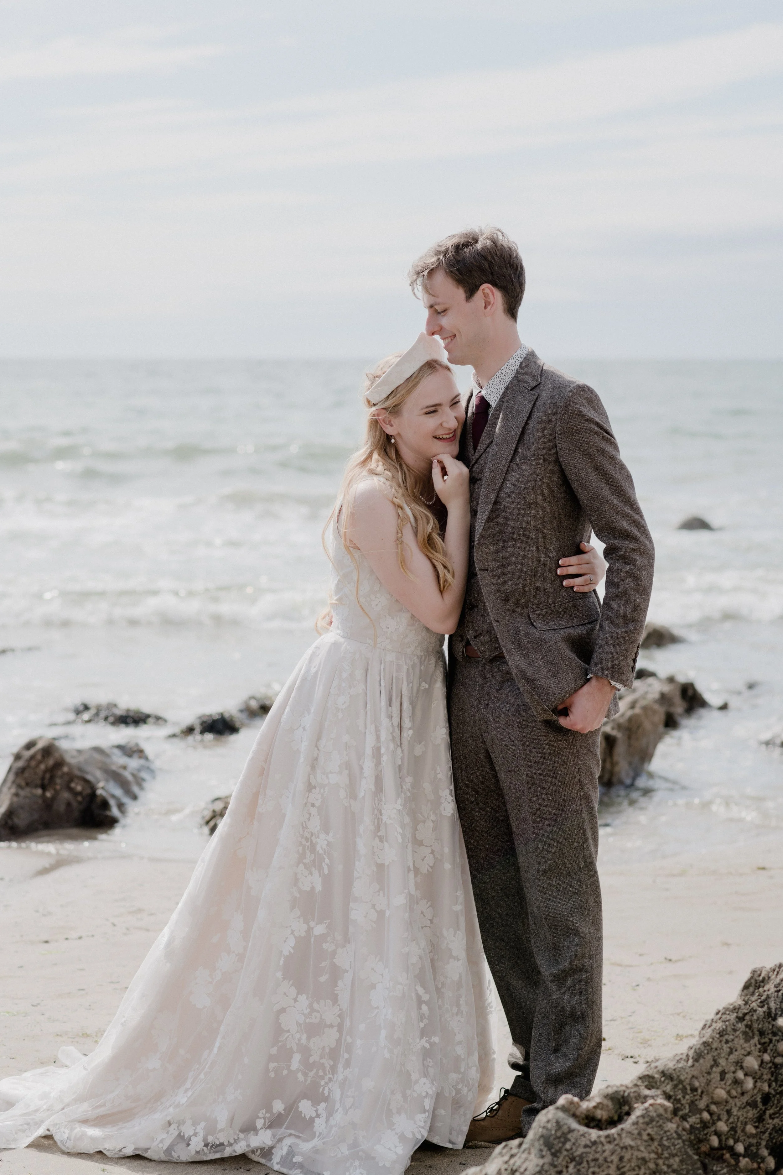 soft and romantic, whimsical reportage wedding photography based in the southwest with a groom in tweed and bride in blush lace against an ocean backdrop for this devonshire beach wedding