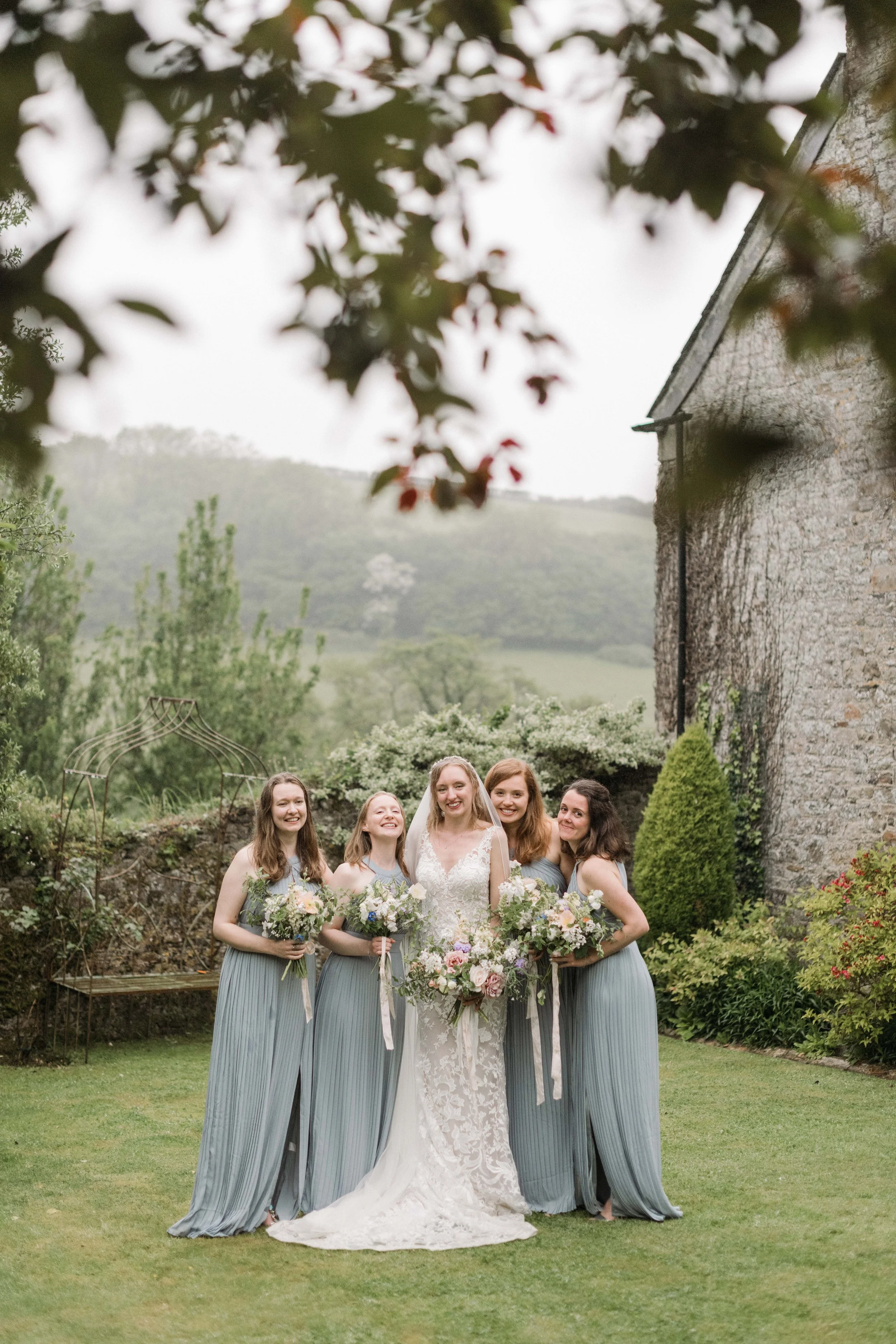 bridesmaids in dusky blue with the rolling hills of Cornwall in the background at pengenna Manor