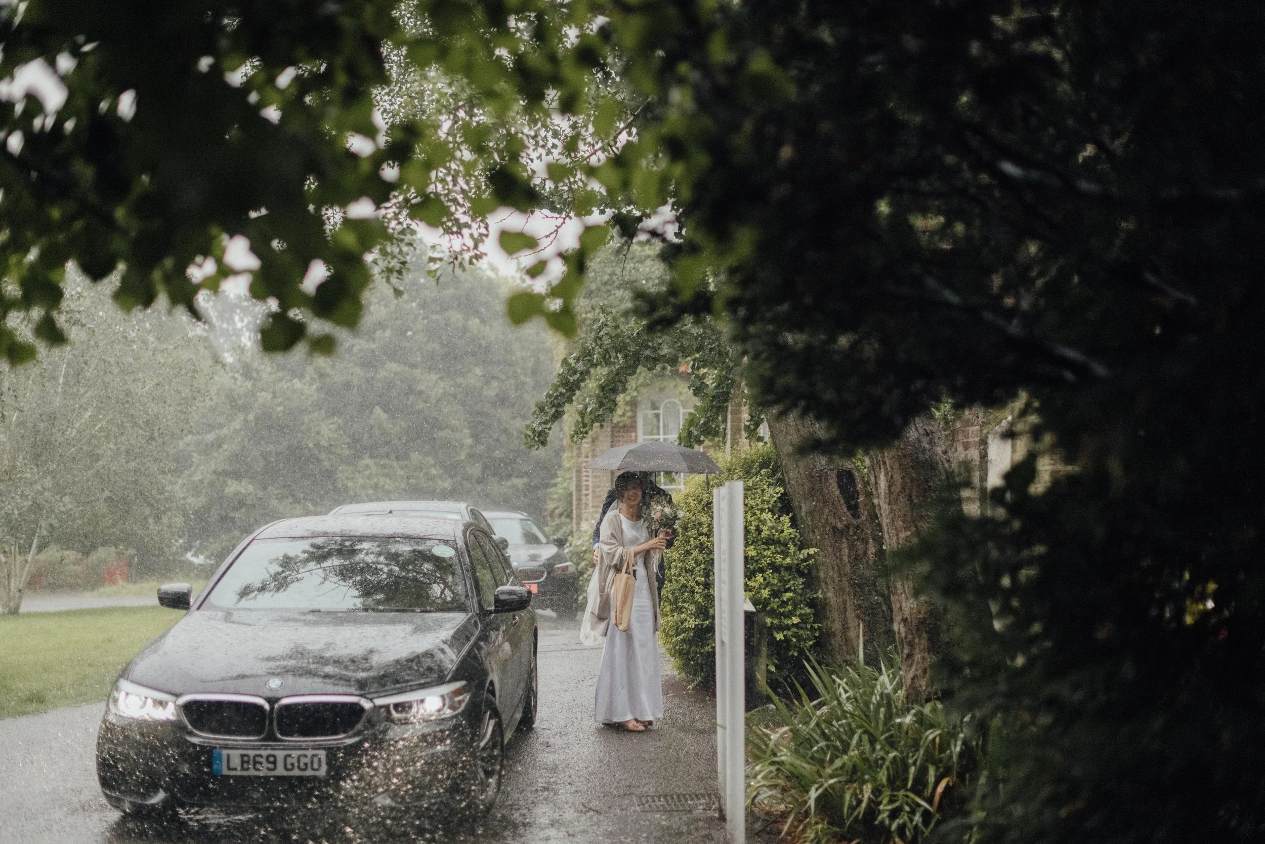 a bride heads to her wedding in the rain at Merton registry office in London