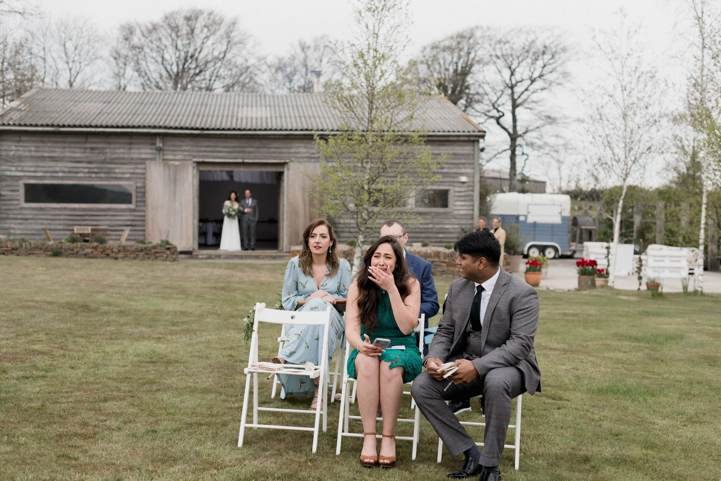 bride makes her entrance for her outdoor wedding as guests look on emotionally, reportage wedding photography captured by Lyra & Moth