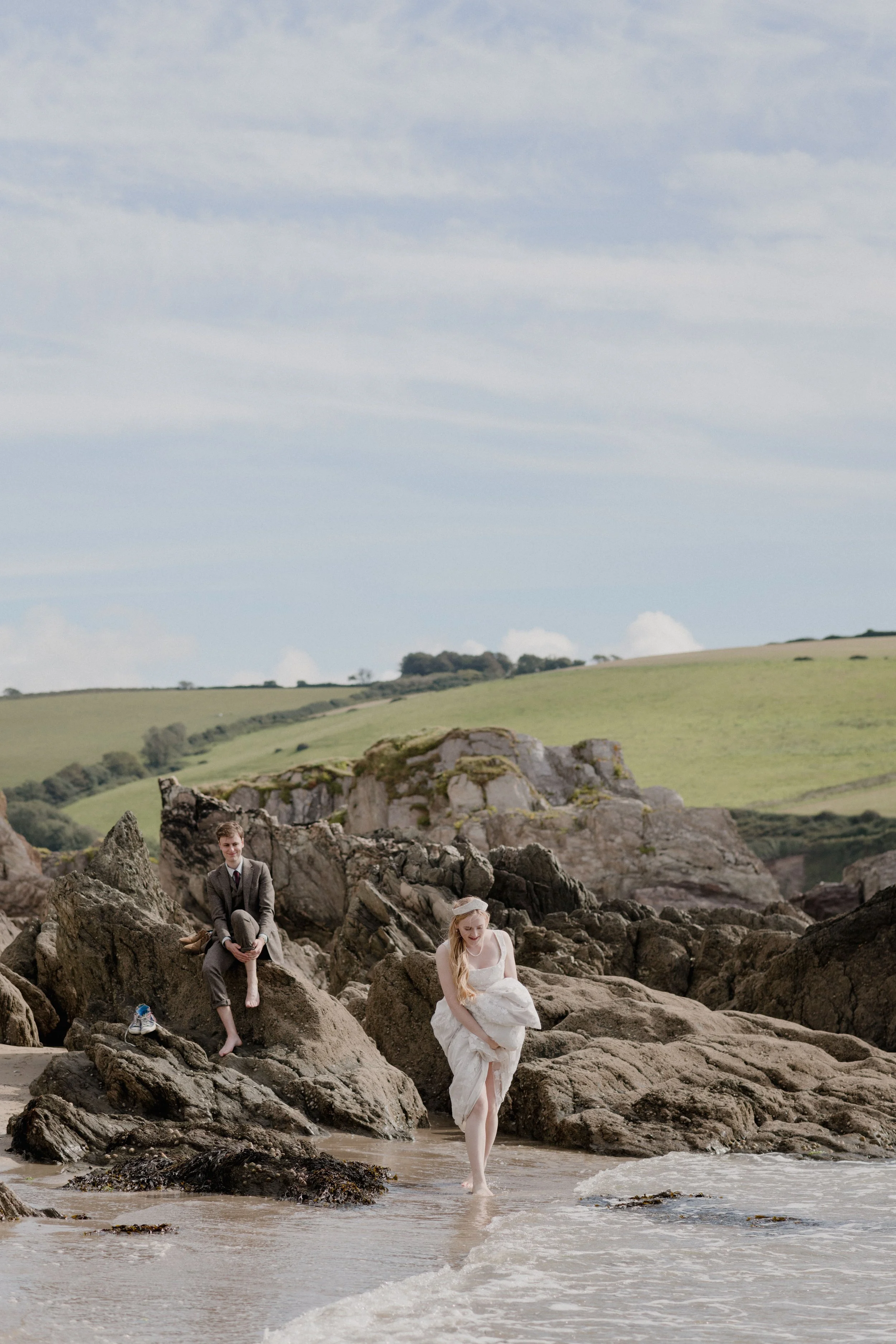 natural and relaxed unposed wedding photography of bride and groom getting into the sea for a dip