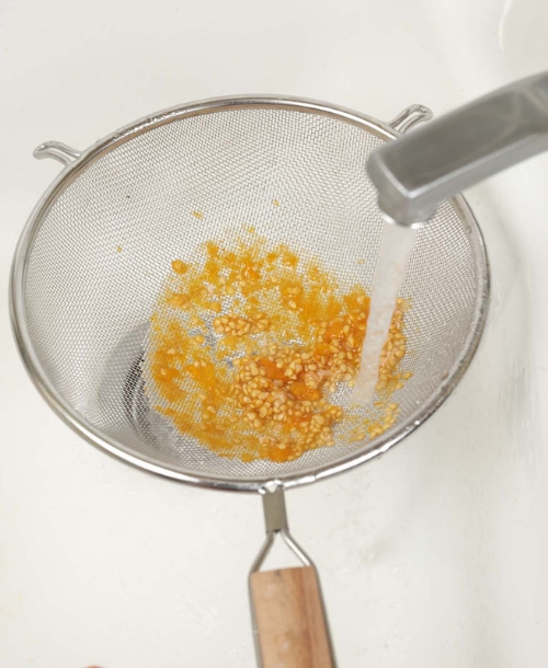 Pour the remaining liquid and seeds into a kitchen strainer and wash the seeds thoroughly under running water. (Photo by Victor Schrager, courtesy of Amy Goldman)