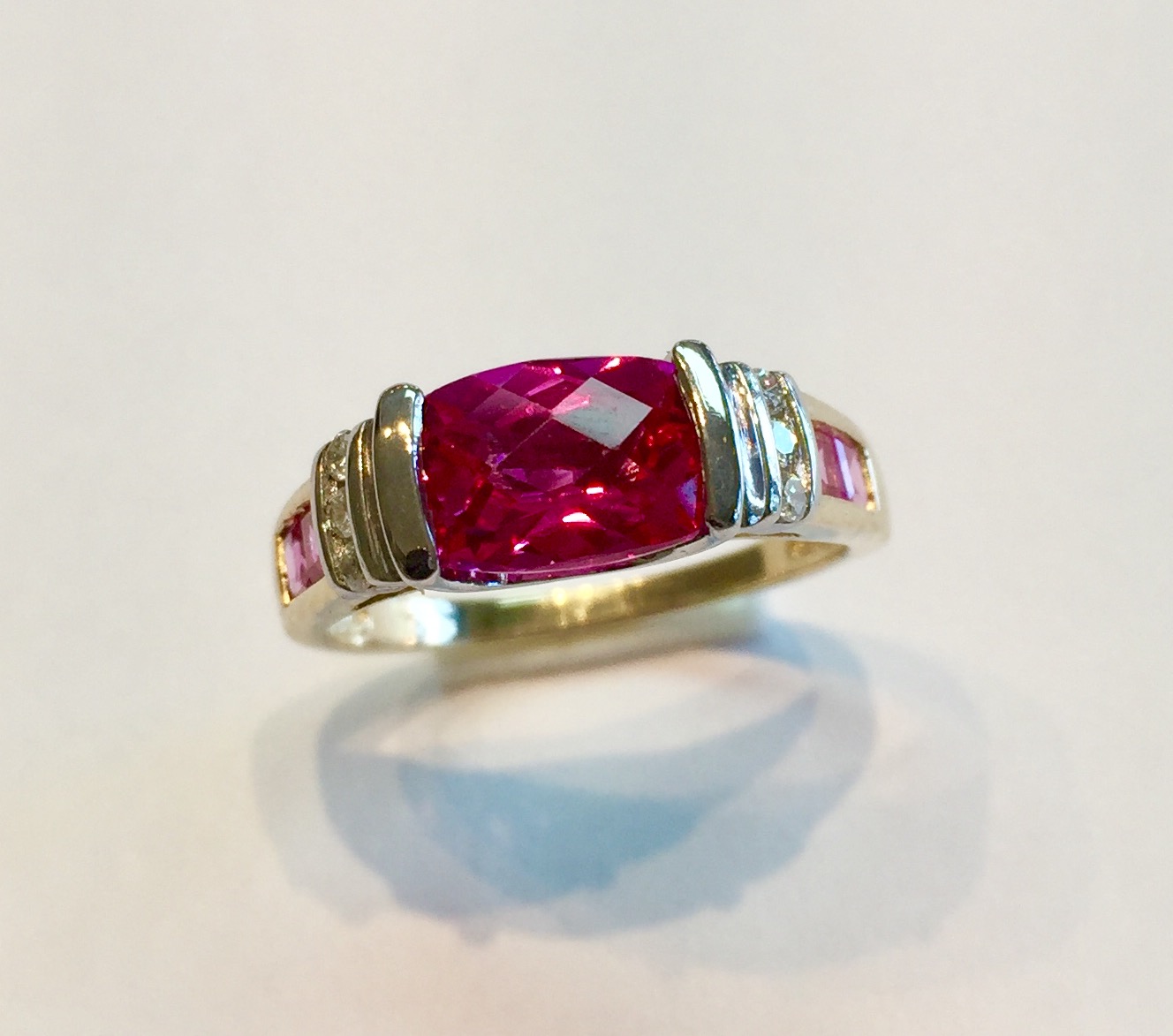 Item No A229 (a) USD675 14K Yellow and White Gold Tourmaline and Diamond Ring This is why I love tourmalines. The pink color is as eye catching as it is vivid. Hard to see in the picture but the ring is white gold on top and the band is yellow gold. The center pink tourmaline is approx 2.1 carats and has a checkerboard cut. There are .06 nice diamonds and two princess cut tourmalines on each side to compliment the main stone. Check out a matching pendant in the gemstone pendant section. Quality and beauty. 