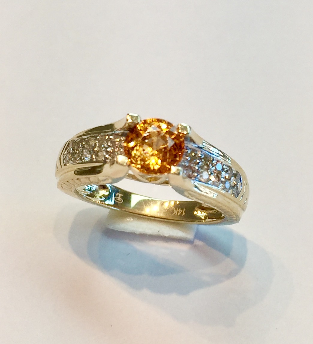 Item No AB52 USD475 14K Yellow Gold Mandarin Garnet Diamond Ring Great fire in this one carat Mandarin/Spessartite/Fanta garnet. One of my favorite gemstones and this one is beautifully set with filagree work down the sides, below the diamonds, and along the edge of the ring. Charming ring. 