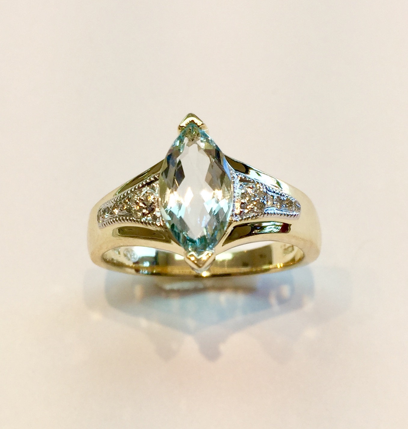 Item No. AB98 USD375 14k Yellow Gold Aquamarine and Diamond Ring Charming quality ring with 1.5 carat of a well cut marquis shaped aquamarine and complimented by quality diamonds and a little mill grain work on either side. 