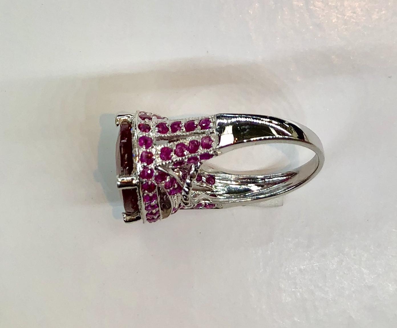 Item no.6 US$1,245 Stamped 14K White Gold Ruby and Diamond Ring Large eye catching designer ring with almost 8 carats of Ruby (15mm x 11mm) in the centre stone. The ruby is surrounded with a halo of another .25 carat of diamonds. There are even small diamonds on the top of the prongs. Fabulous workmanship in all of this piece and especially in the inlaid rubies around the gallery and upper shank. If you like stunning, big and unique rings this is definitely worth seeing. The centre ruby is a genuine high quality enhanced natural ruby. Crown of the ring measures 19mm x 13.6mm 7.8 grams