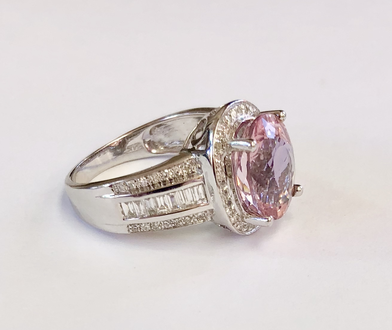Item A111 USD 995 14K White Gold Tourmaline and Diamond Ring The pink tourmaline (3.5 Carat) is superbly complemented by the white gold, the halo of quality diamonds and the fabulous baguette diamond dow the size. This ring has a contemporary and very classy feel and look to it. 