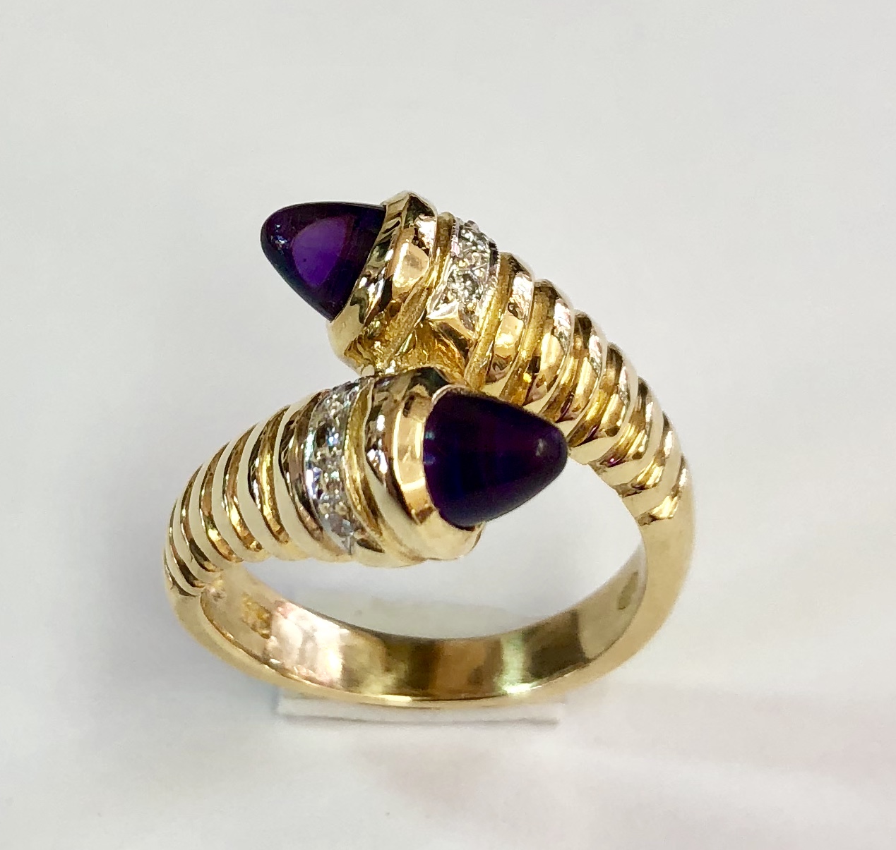Item no. 390 US$495 Stamped 14k Yellow Gold Amethyst and Diamond Ring. This designer cross over ring is probably a one-off. Cabochon amethyst, white diamonds set in a little bit of white gold, very attractive design, quality workmanship and you will be the only one who has one. 7.9 grams