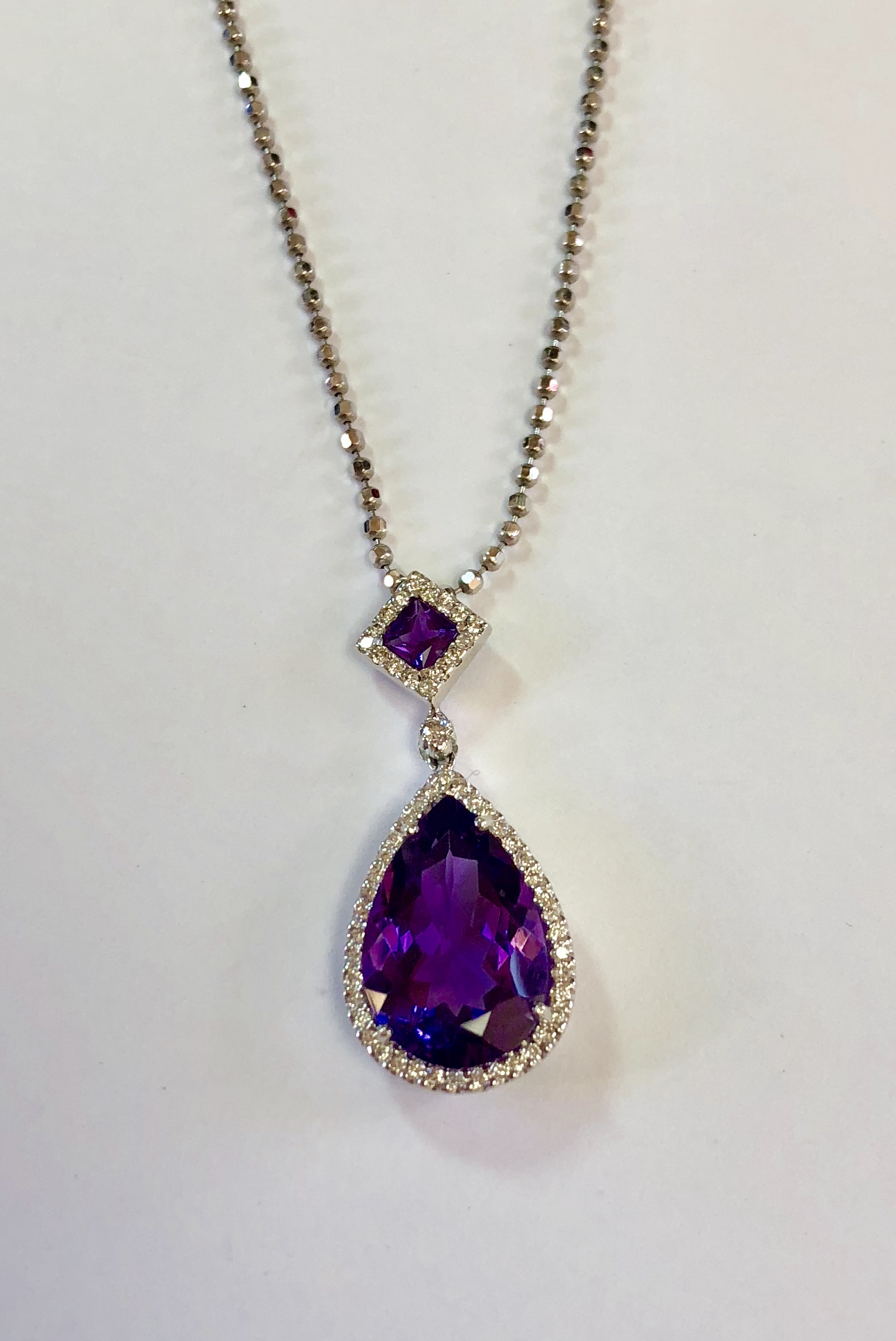 Item No. A93 USD745 18K White Gold Amethyst and Diamond Pendant with 14K Chain. Superior quality gemstones in this shimmering pendant. Approximately 6 carats of amethyst in a square and a pear shape, surrounded by a halo of fine quality diamonds Matches perfectly with ring no A94 for USD545 or USD1,290 for the set. 6.5 grams
