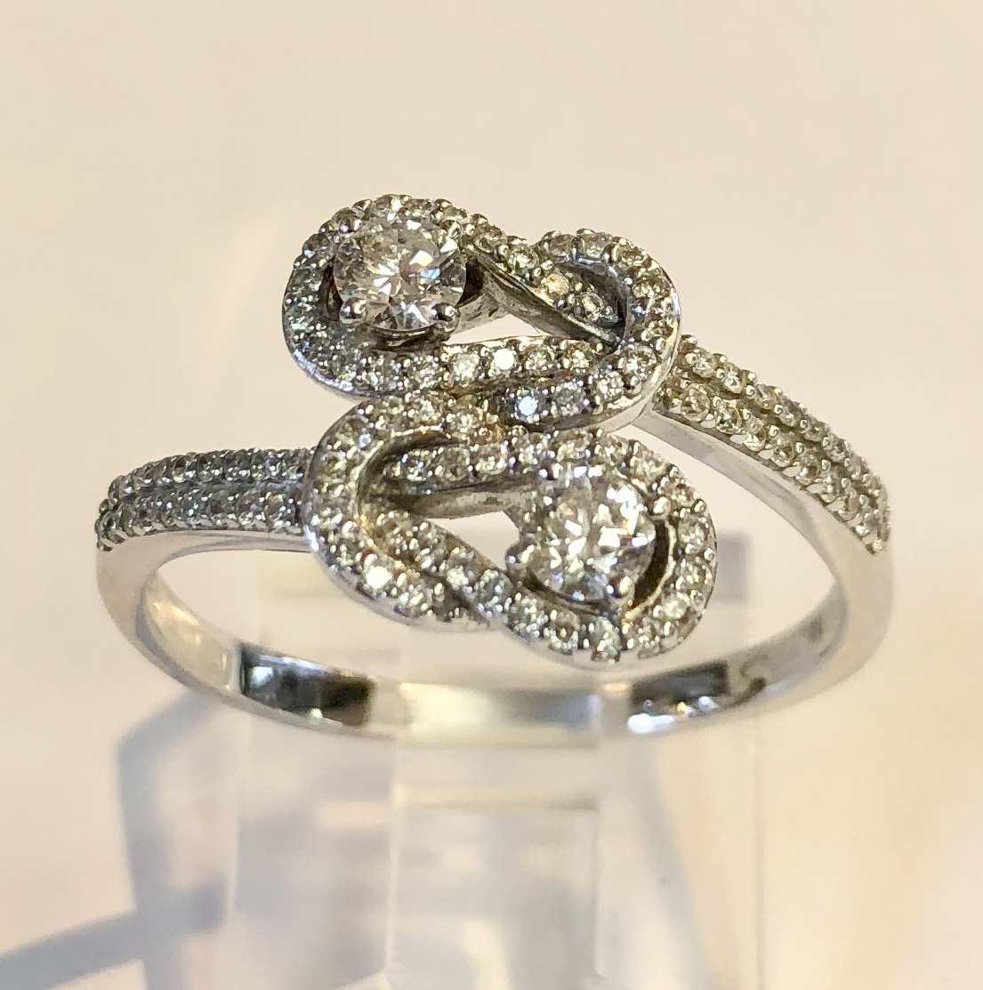 Item no. 298 USD695 Stamped 14k White Gold Diamond Ring. 'Double knotted' cross over ring with two high quality round diamonds in the centre of each knot, weighing approximately .14 carat each. 92 smaller diamonds highlight the larger ones and make this a delightful piece of jewellery. 4.1 grams