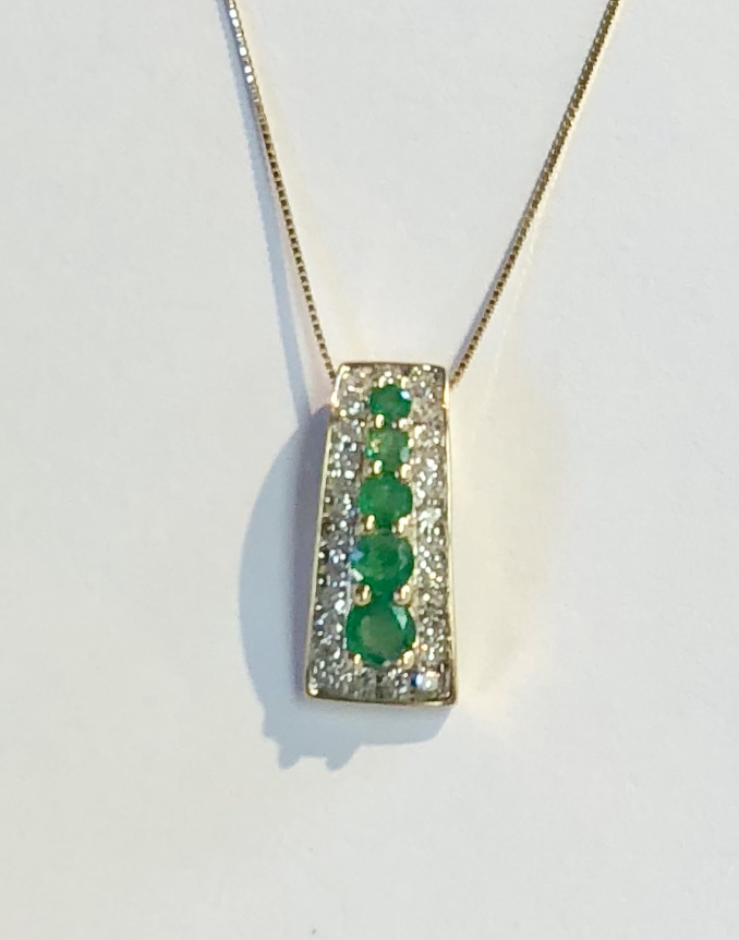 Item no. 42 USD395 14K Yellow Gold Diamond and Emerald Pendant with a 14K Chain. 5 ascending quality emeralds weighing approximately .68 carats surrounded by a halo of diamonds weighing .28 carat. Outstanding value.
