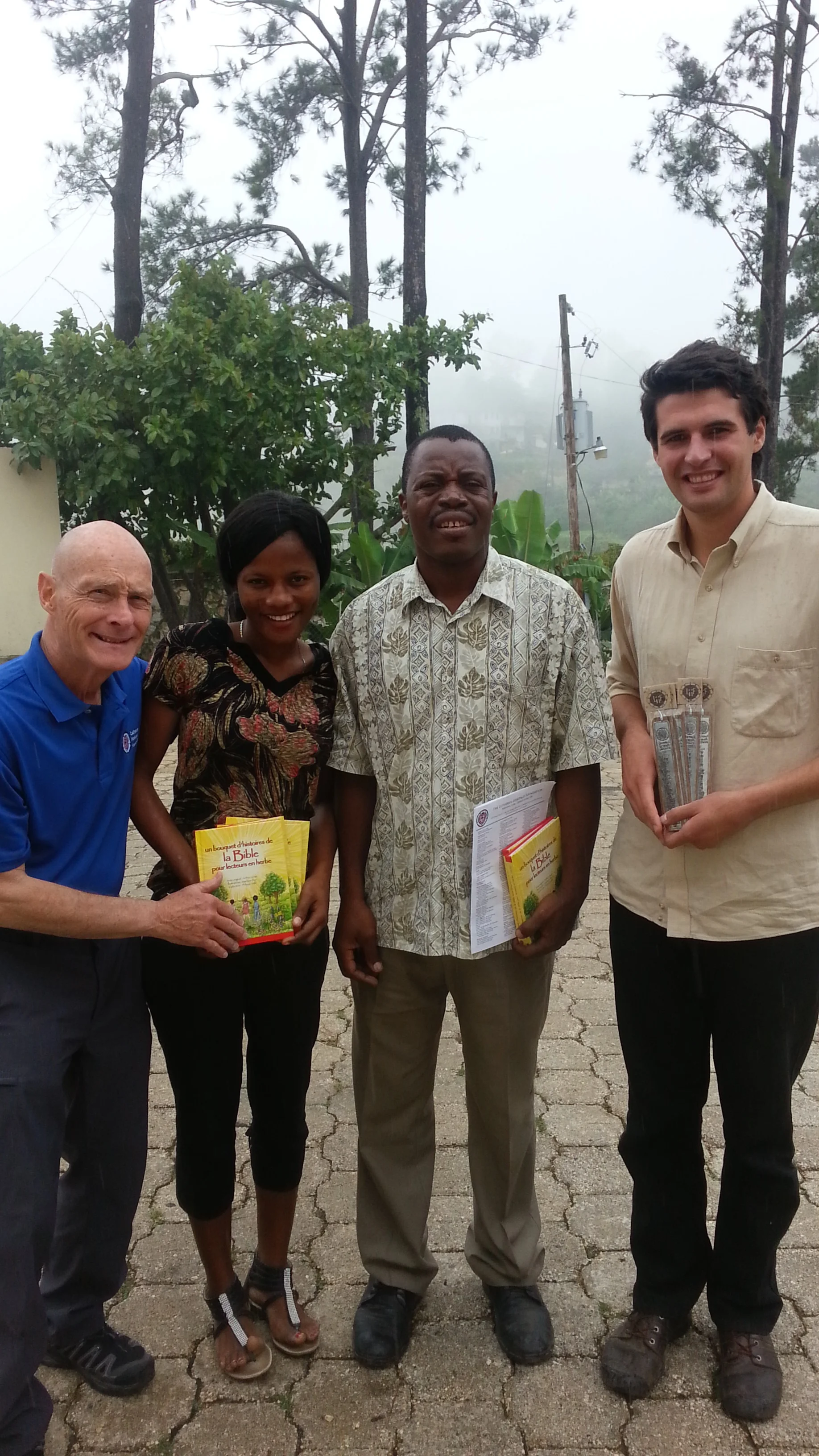 Photo of Rev. Larry Rockemann, Elaine, Rev. Daniel Paul and Ben Wiseman, NEHLM Liaison receiving picture story Bibles. 