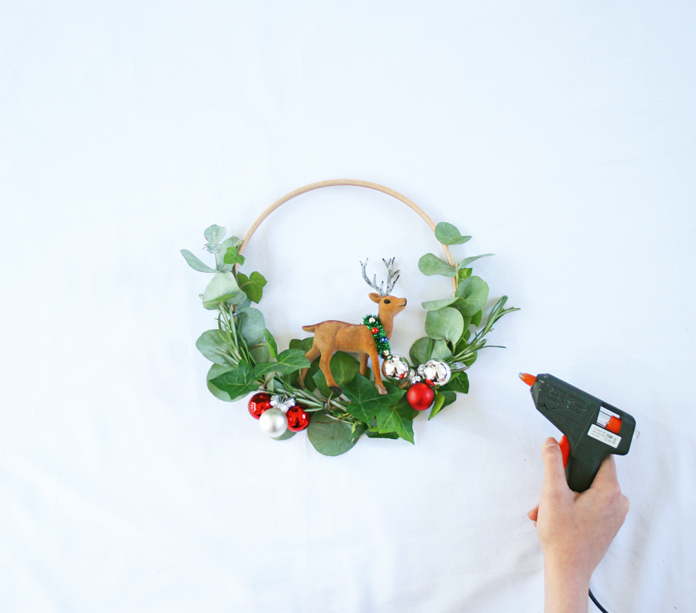  3 Remove any hanging loops from your tree decoration, then glue it securely to the centre of the hoop base using a glue gun. Leave the whole hoop piece aside to dry. 