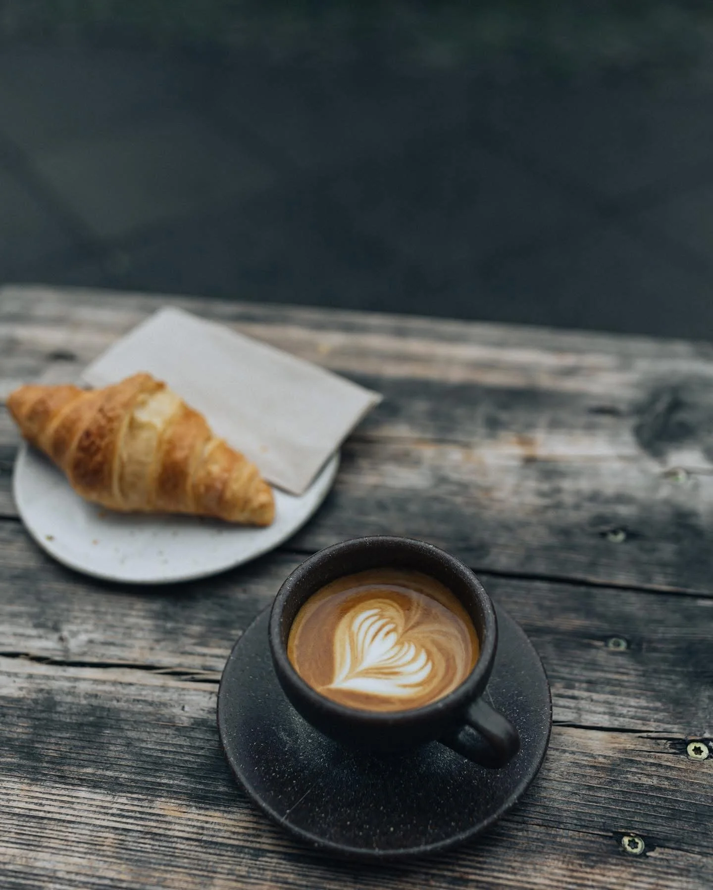 Cortado and croissant served on a wooden table at Oslo Kaffebar in Berlin Mitte