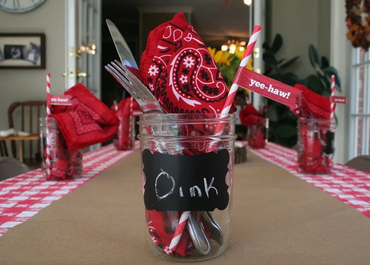 The tables were set with red and white checkered cloths and brown kraft paper. Mason jars containing bandana napkins, silverware and cutsie straws with pennants were at each place setting.