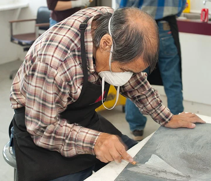Qiatsuq Niviaqsie clears an old image off a slate block.