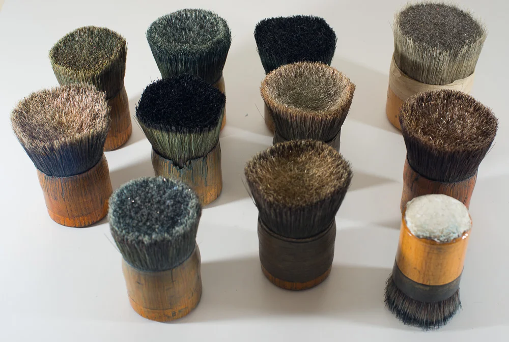 An assortment of old stencil brushes. It appears like horse hair inserted into bamboo sections with a wooden end cap to top it off. Often the printers will customize tools to suit themselves and here you can see insulation attached to the handle with double sided tape to give the printer some relieffrom the repetitive impact on their palms.