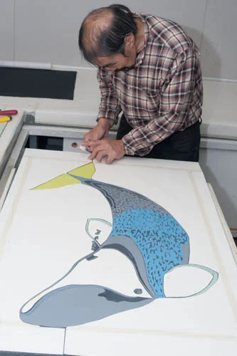 Qiatsuq is preparing the templates. Notice that there are templates in each of the flippers, the head and on each side of the body that cover the non image areas. He tapes the two sides of the template together so it doesn’t move during the printing process. Qiatsuq is known for his careful and deliberate manner, excellent attributes for a stone cut printer.