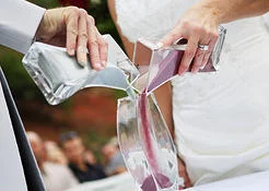 "Your union will now be symbolized through the pouring of these two individual containers of sand. Each color represents you, (names of bride and groom), and all that you were, all that you are, and all that you will ever be before this union. As your individual sands come together it reminds us that “neither is the man without the woman, neither the woman without the man, in the Lord”. I ask now that you each take your sand and pour them into the one vase." (the sand is now poured). While the sand is being poured, the officiant says, "(names of bride and groom), while it’s important that you both maintain your individuality, it is our hope that you will become as inseparable as these grains of sand, and always find yourselves to be one in love, commitment and joy." “___________________ and ________________ the two lighted candies symbolize your separate lives, your separate families and your separate sets of friends. I ask that you each take one candle and that together you light the center candle. The individual candies represent your individual lives before today. Lighting the center candle represents that your two lives are now joined to one light, and represents the joining together of your two families and sets of friends to one.” http://www.vowsoftheheart.com/ceramonies/unity-candle-wedding-ceremony/ http://www.sayanythingceramics.com/sand-ceremony-wording.php