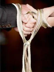 "Officiant: (Bride) and (Groom), you have just sealed your relationship by the giving and receiving of rings. Today this relationship is further symbolized by the tying of a lover’s knot. At this time, I invite (Bride) and (Groom)'s mothers to come forward to represent their respective families. These families have raised and nurtured this man and this woman and helped them become the person each holds most dear. It is right and fitting to acknowledge that now these two previously separate circles of love are being united in a new and wider circle. ____, please drape the cord over your son's wrist. It represents the wishes and blessings your family bestows upon your child, all that he is now and all he may become. ____, please drape the cord over your daughter's wrist. This cord represents the wishes and blessings your family bestows upon your child, all she is now and all she may become. ____ and ____ please tie these cords over your children's hands as a visual symbol of the joining of your two families through their hearts, bodies and souls. May their marriage endure in faith and fidelity knowing they have the blessing and support of the families that gave them life, hope and love. (Bride) and (Groom), woven into this cord, within its very fibers, are all your hopes and dreams. With the fastening of this knot I secure the love and happiness wished here on this day for your new life together. May this cord draw your hands together in love, never to be used in anger. May the pledges you have made never grow bitter in your hearts. Two entwined in love, bound by all which brings strength to this union. Hold tight to one another through both good times and bad, and watch as your strength grows. Your bond is not formed of the knots of this cord, but instead by your pledges to one another. May your bond never be broken." http://www.brevardminister.com/1/post/2012/09/a-ritual-of-unity-the-knot-ceremony.html