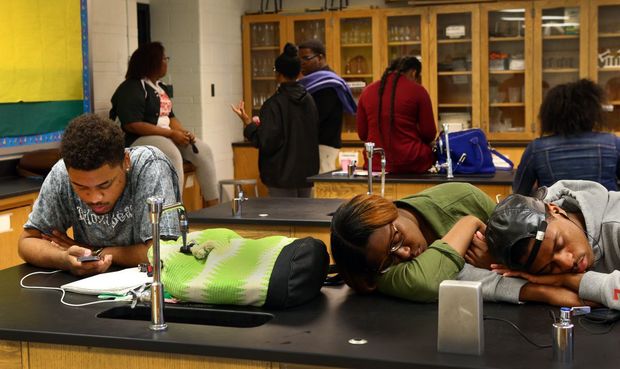 Normandy High honors student Cameron Hensley (left), a senior, checks his phone as some students sleep away physics class on Thursday, April 30, 2015. Though the teacher was inside the classroom the entire class period, no instruction occurred. Instead, the teacher and many students spent the hour on their phones or practicing for the dance team's upcoming parade. Photo by Robert Cohen, rcohen@post-dispatch.com