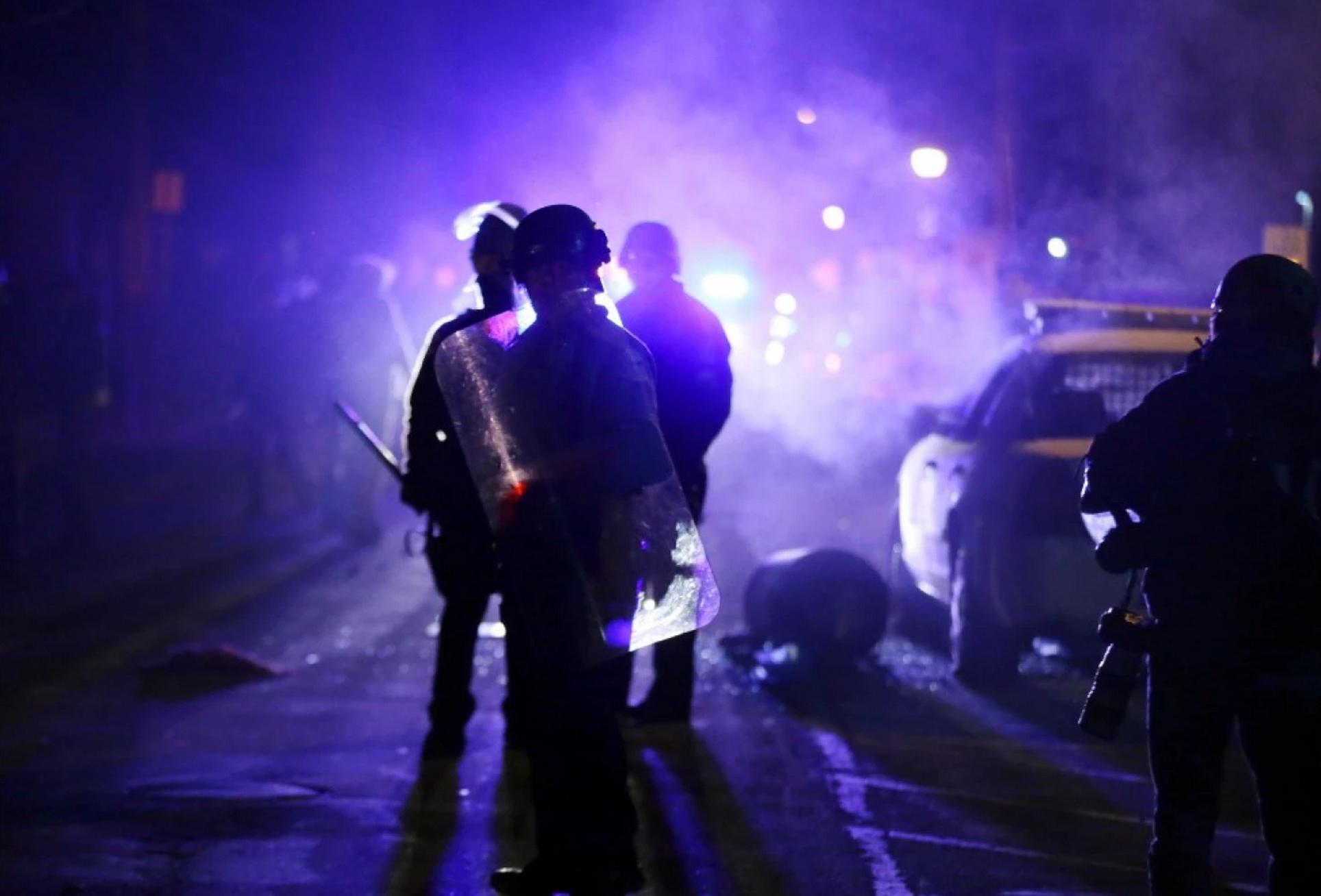 Police officers watch protesters as smoke fills the streets in Ferguson, Mo., in November after a grand jury’s decision in the fatal shooting of Michael Brown. (Charlie Riedel/AP)