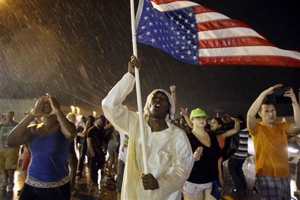 Protesters march in the rain, Sunday, Aug. 9, 2015, in Ferguson, Mo. S Jeff Roberson / AP