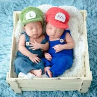 Newborn twins dressed as Mario and Luigi in a wooden crate