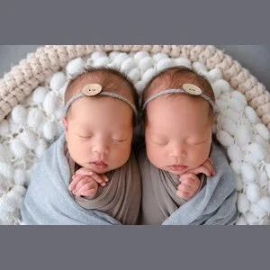 Sleeping newborn twins wrapped in grey with delicate matching headbands