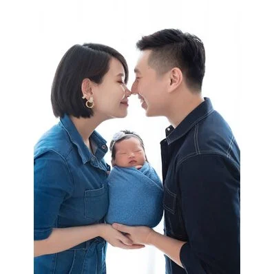 Parents kissing while holding their newborn wrapped in blue