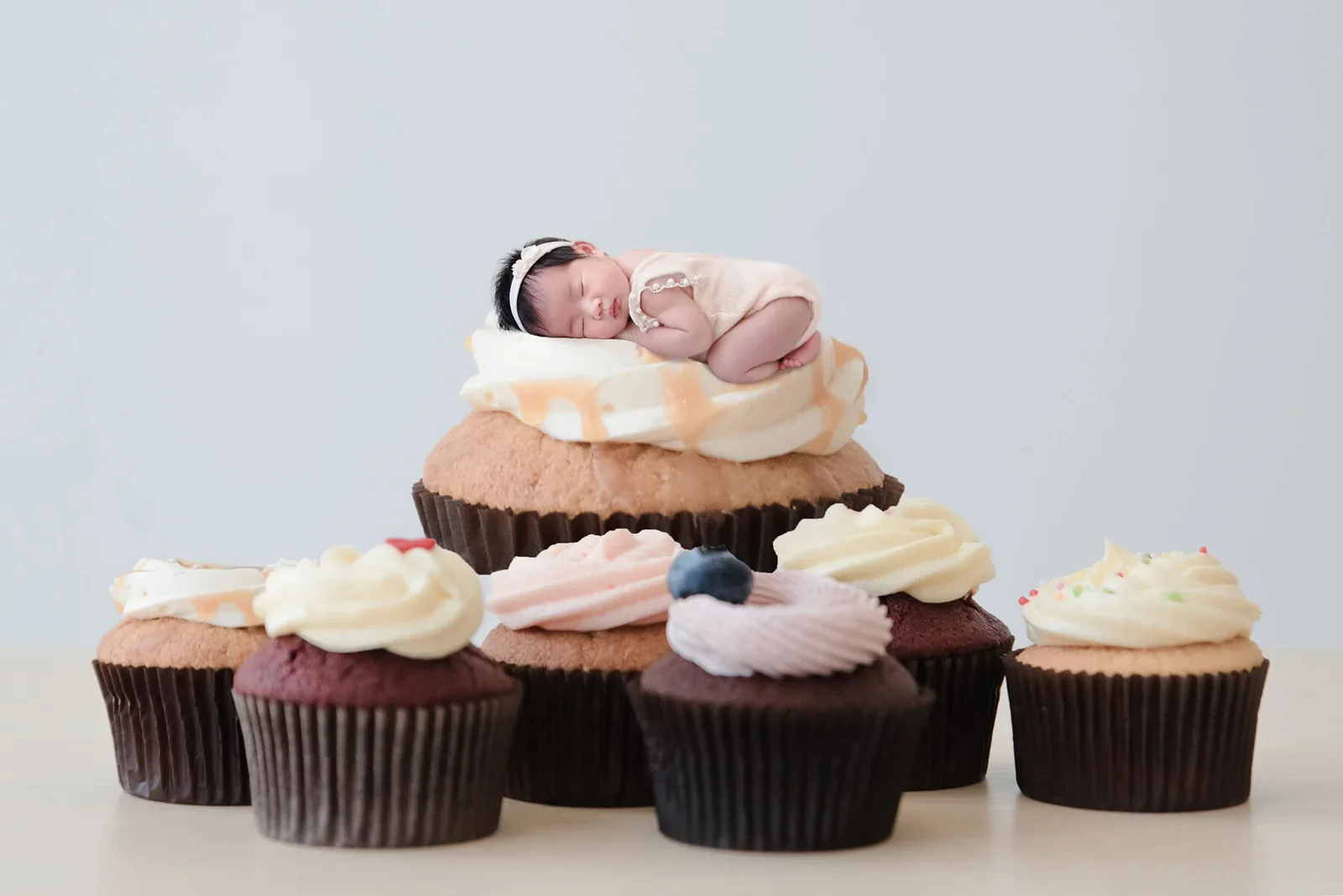 Sleeping newborn on a cupcake in a digitally composed dessert scene