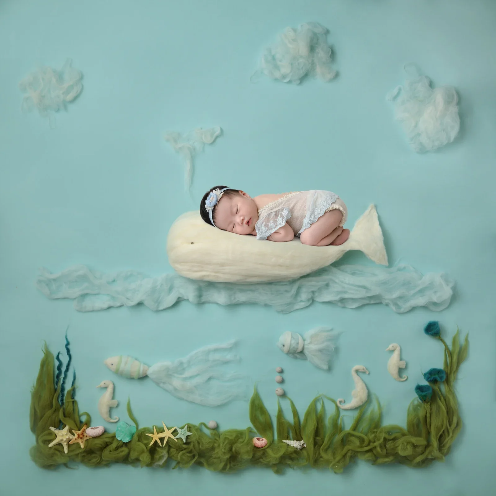 Sleeping newborn resting on a cream whale above sea plants and seahorses in a digital underwater composition