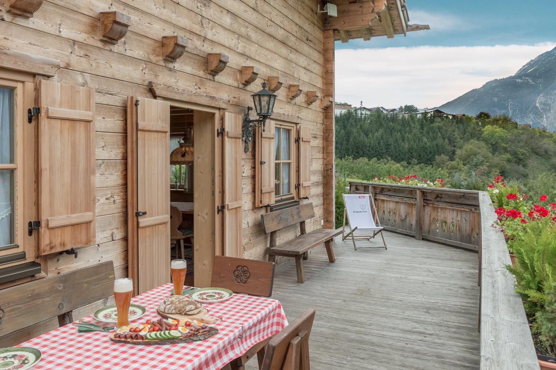 Holzterrasse des Ötztal Chalets in Tirol mit gedecktem Holztisch und Tiroler Jause im Freien.