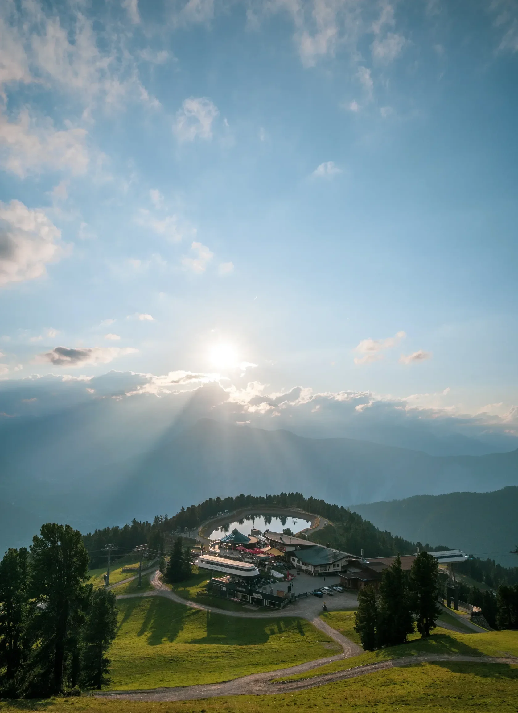 Luftaufnahme von Hochoetz im Sommer kurz vor Sonnenuntergang mit Blick auf die Lechtaler Alpen im Hintergrund.