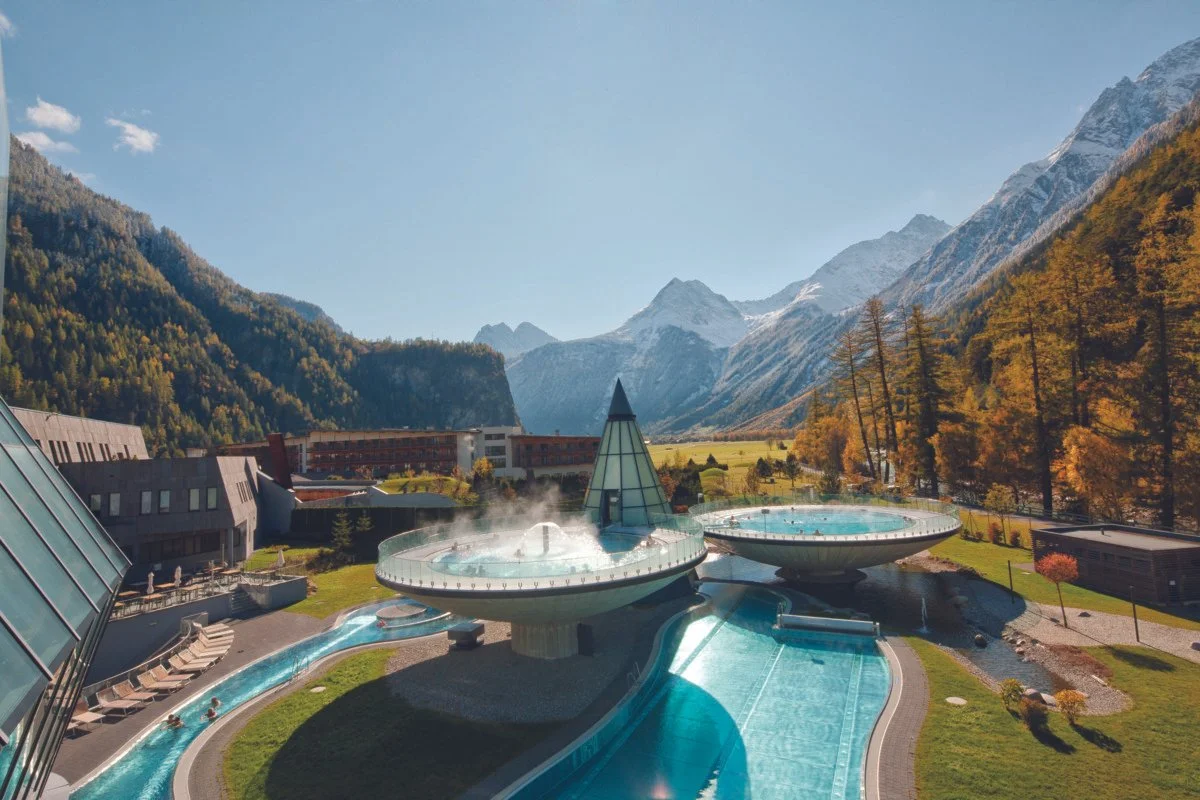Außenaufnahme des Aqua Dome in Längenfeld an einem Herbsttag mit bunter Landschaft und Bergkulisse im Ötztal.
