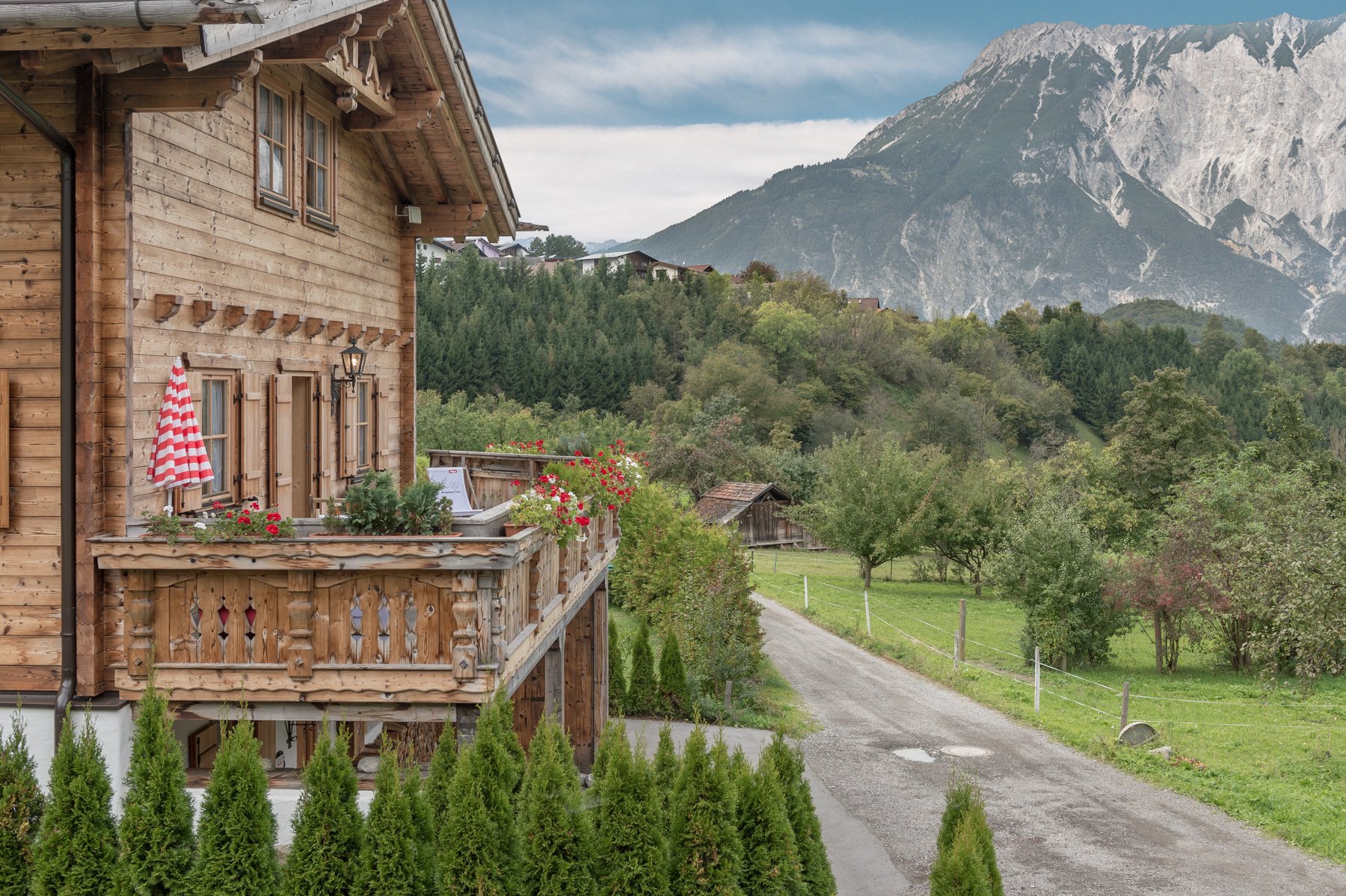 Außenaufnahme des Ötztal Chalets in Sautens mit Terrasse, umliegenden Wiesen und Blick auf das Tschirgant Massiv.