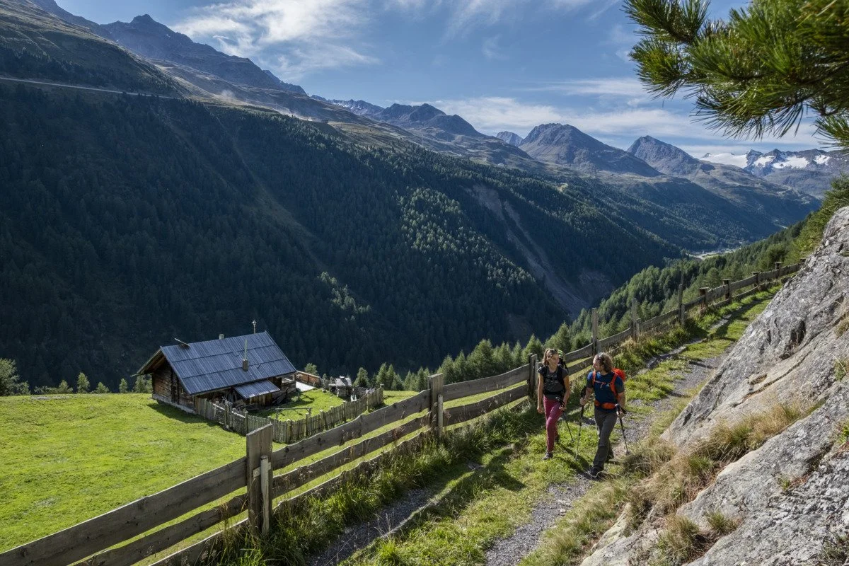 Zwei Wanderer auf einem Höhenweg im Ötztal mit Blick ins Tal, unweit des Ötztal Chalets in Tirol.