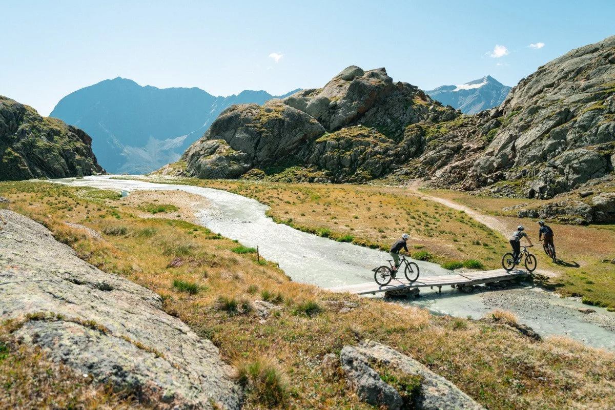 Drei Biker überqueren einen Gebirgsbach im Ötztal in Tirol.