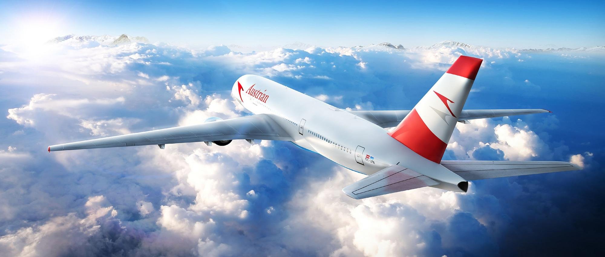 Ein Passagierflugzeug mit Austrian Airlines Logo fliegt über Wolken in einem klaren blauen Himmel.