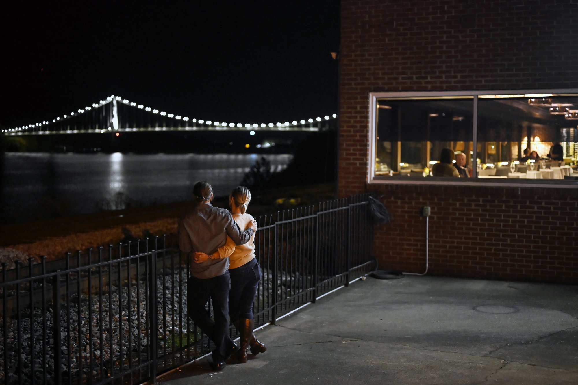  John Meng, 46, and Christie Toffan, 47, embrace while looking toward the Ohio River and the Simon Kenton Memorial Bridge at night near Capronis Restaurant, where they attend a community event of the Rotary Club of Maysville. The couple is passionate