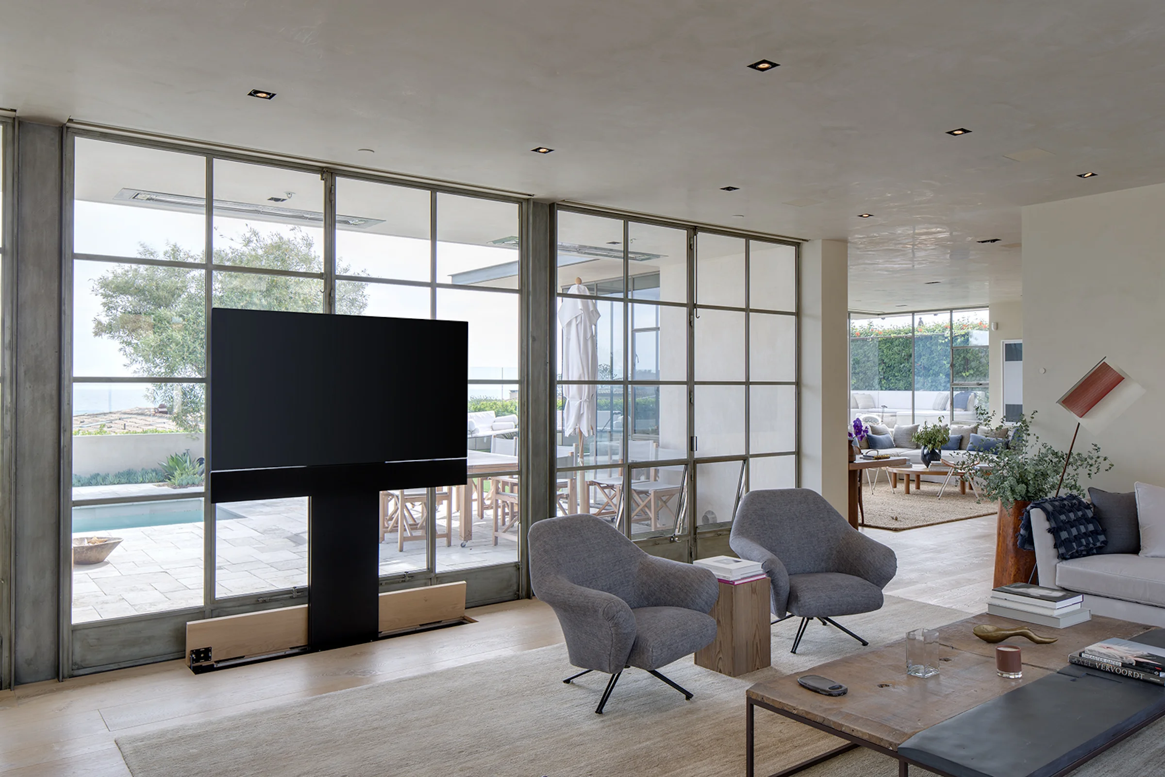 A living room with a television near large window panes