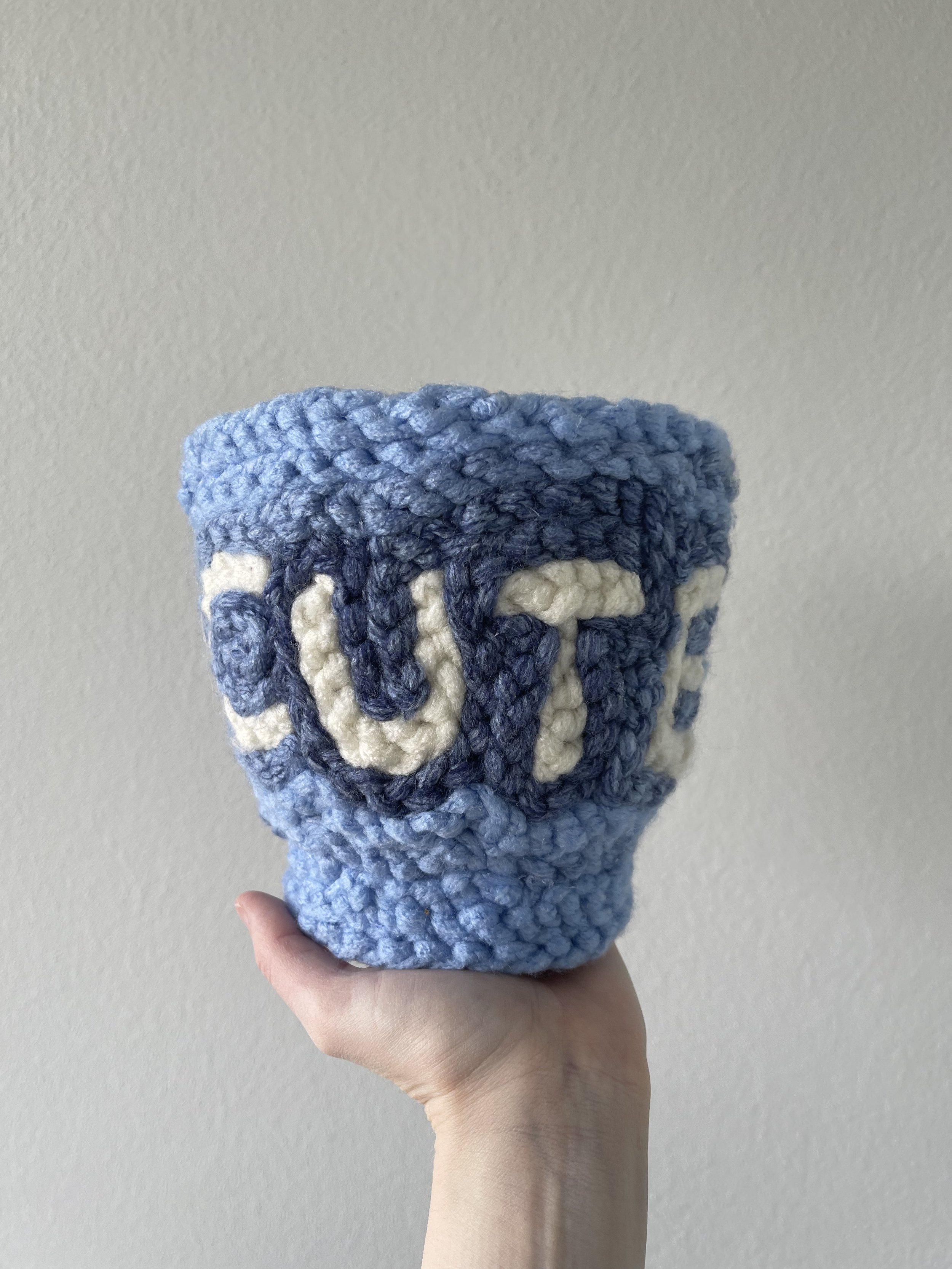 'Cute' finger-knitted yarn on pot plant holder, 2022