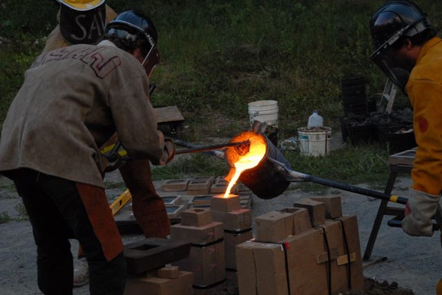 Pouring iron into the mold with the two handed laddle