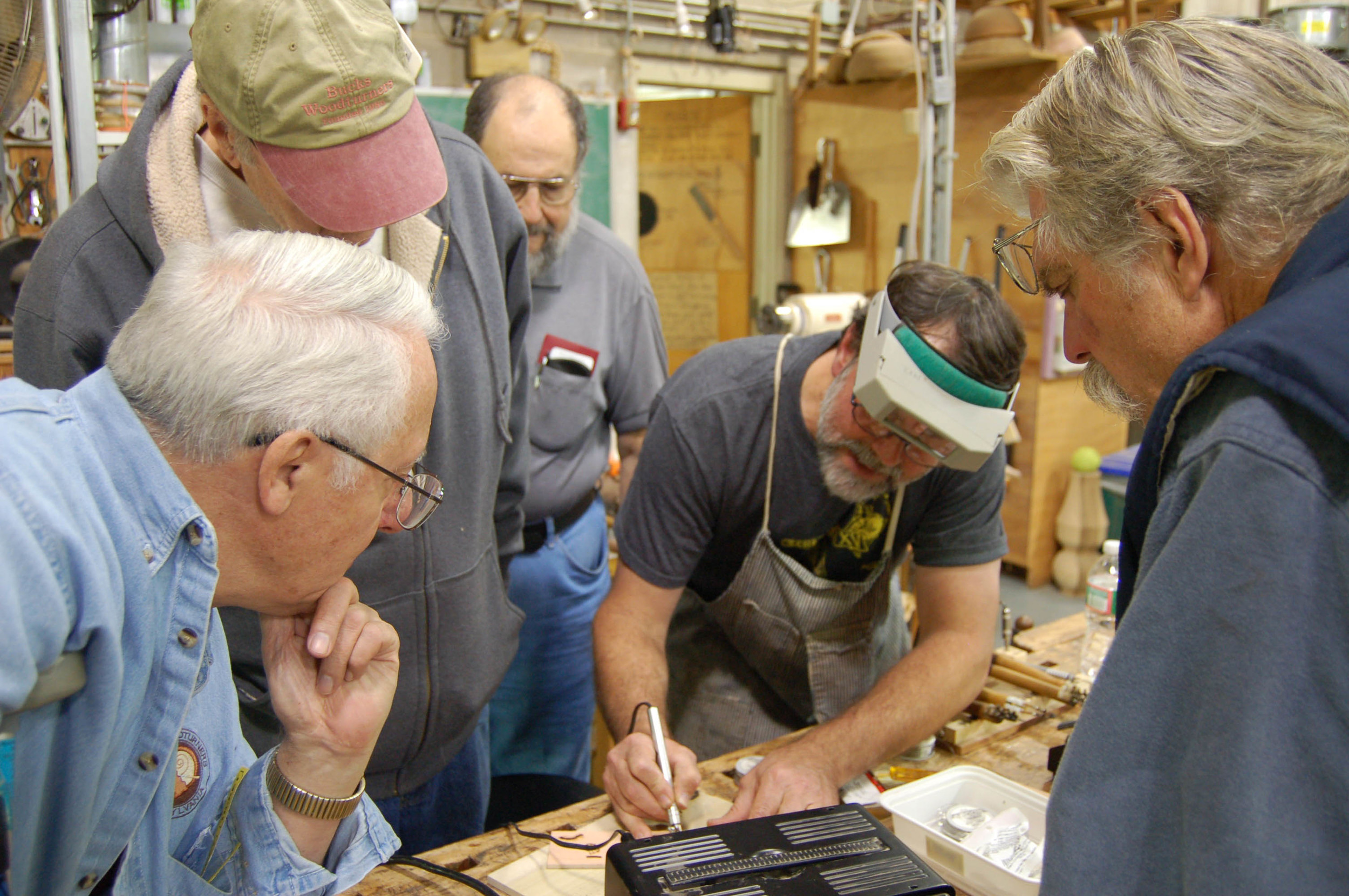 Tom Gall, Tom Barnes, Joe Seltzer, and Mike Tanner watch as Michael Kehs scribes a line.