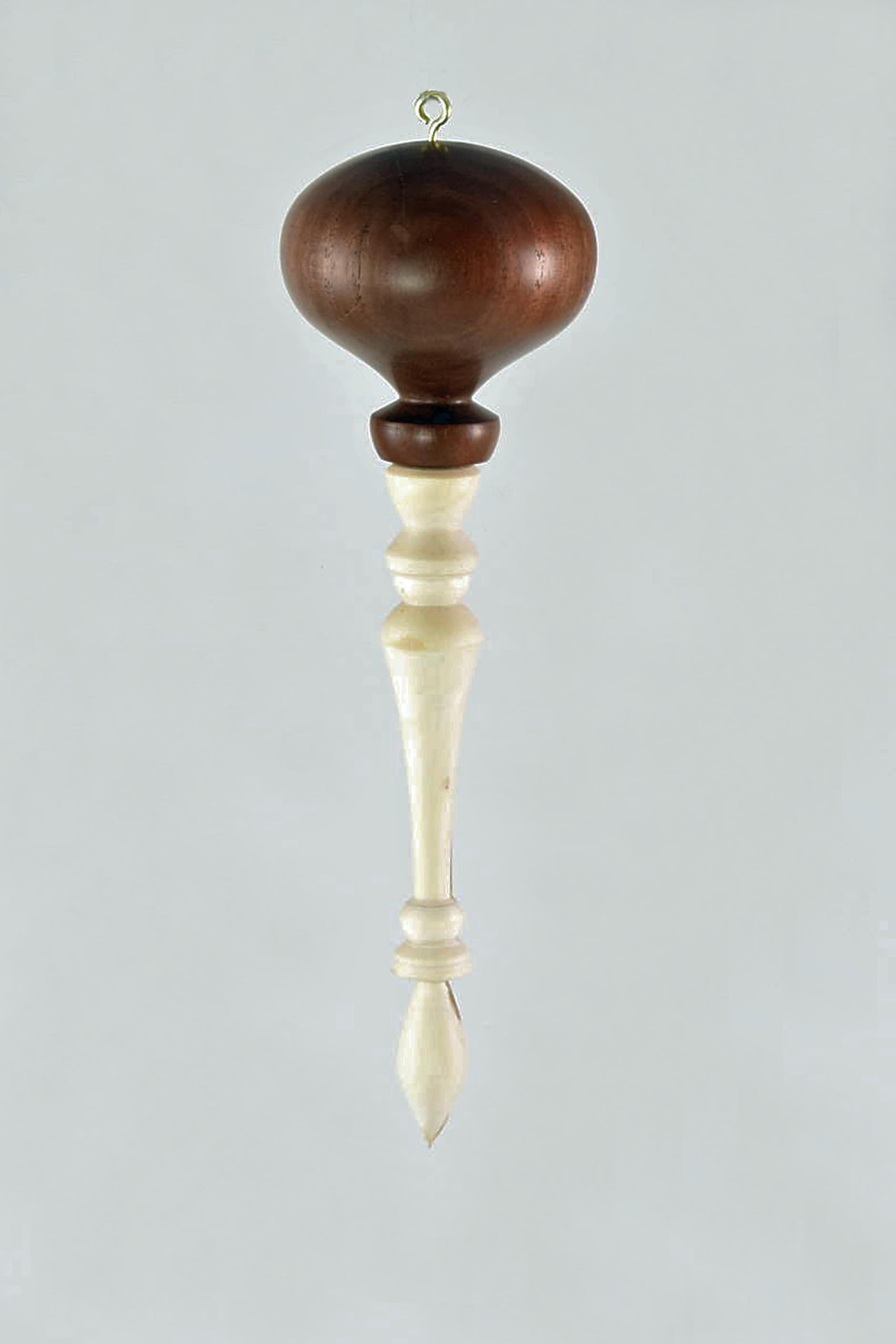 There was a beautiful street tree (Prunus virginiana - chokecherry) on my Philadelphia block that had been knocked down by a truck. I made the finial from a small branch of the tree, as an experiment really, thinking it would crack. But it didn't, so I found a pretty walnut scrap for the contrasting top. -Lise Bauman