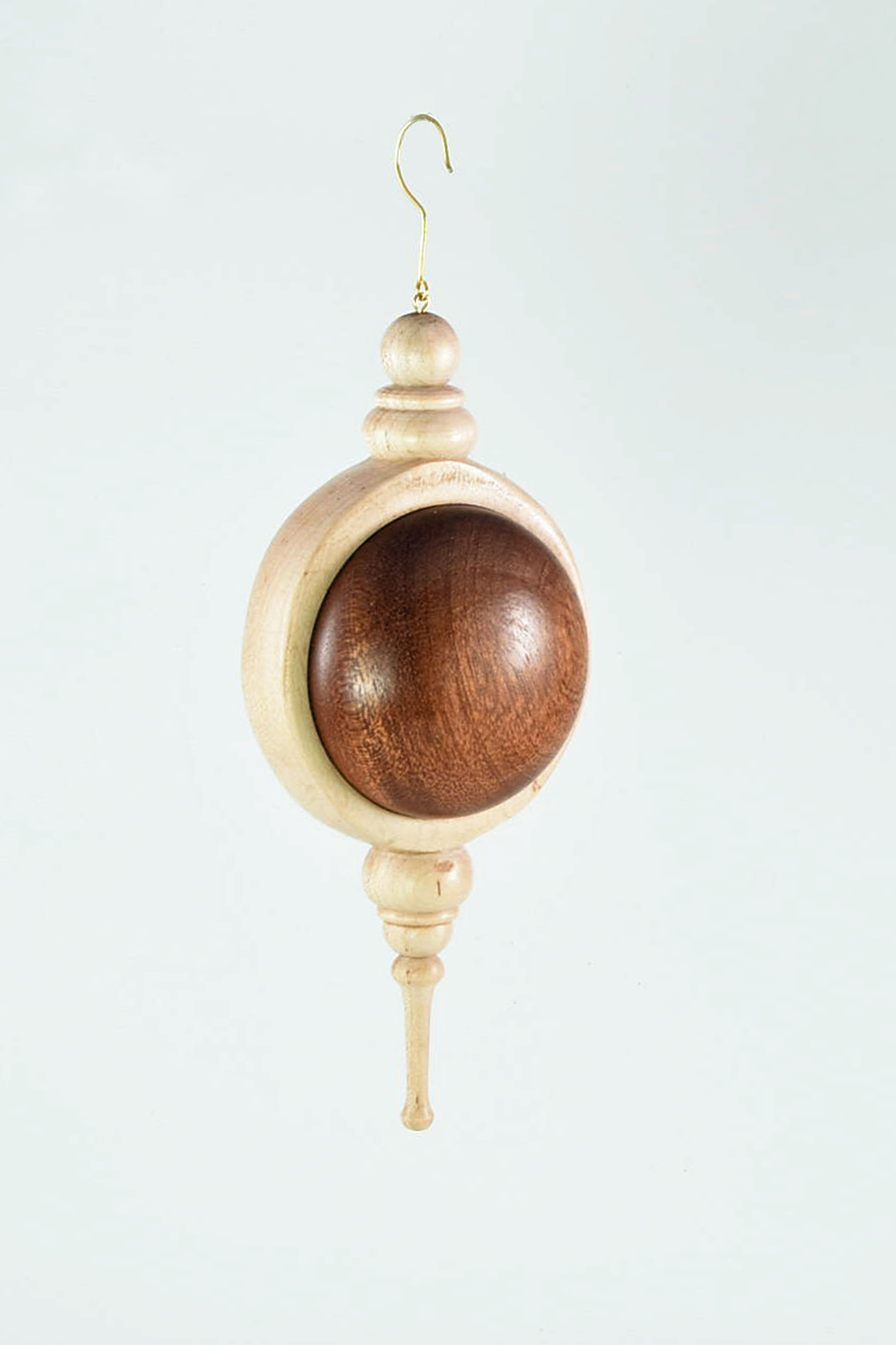  This ornament is made from one piece of maple turned on 2 axes and 2 pieces of Brazilian cherry. Although it might look clunky, it is fully hollowed and quite lightweight. It is made using the method of turning a wooden canteen shown by Tim Yoder on YouTube. -Nancy Rourke