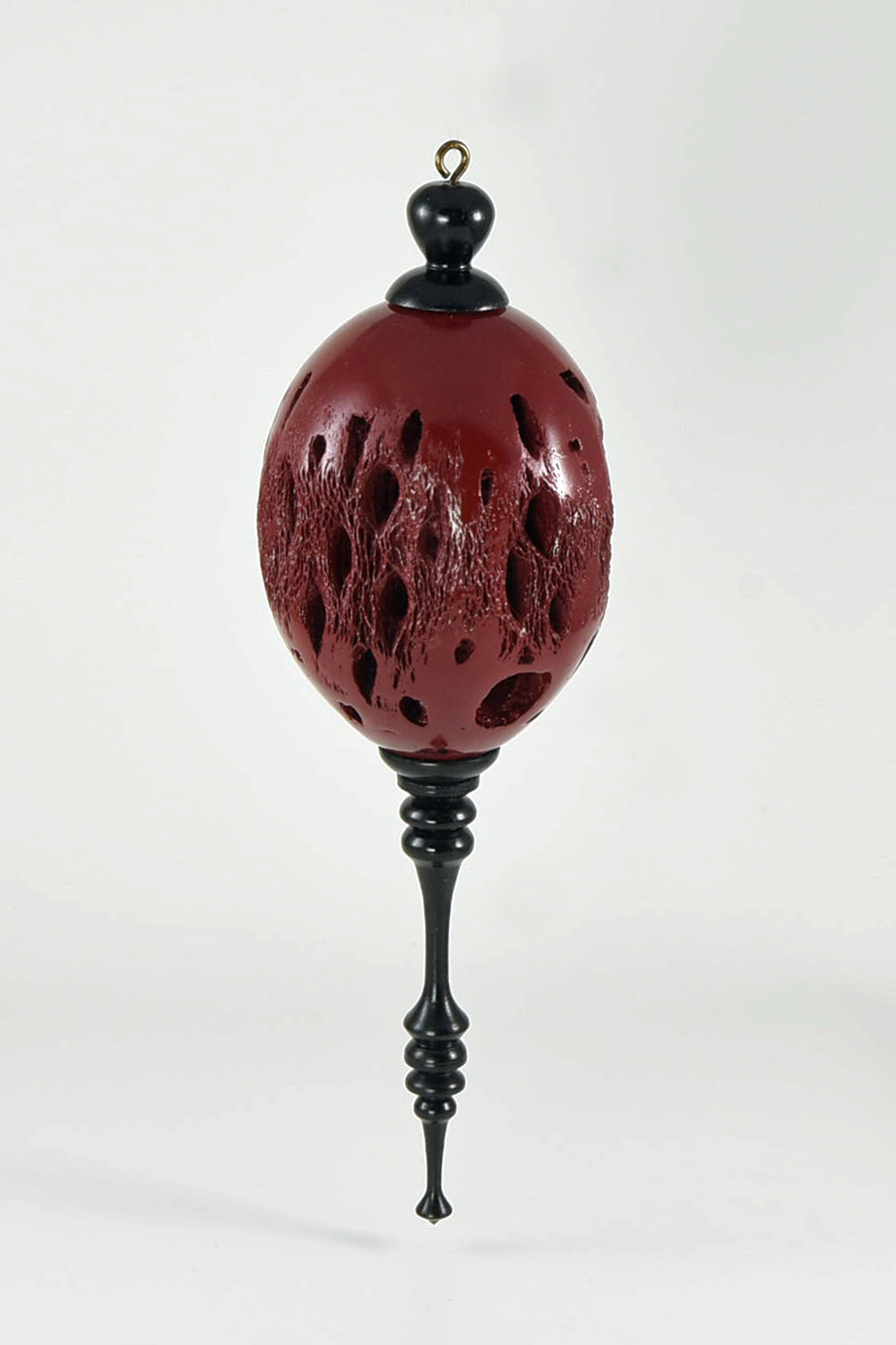 This ornament is made from cactus cholla, the support structure of cacti. As the cholla is hollow inside so I had to add two end pieces to take the finial and the top hook. The whole thing is painted with a high gloss spray paint, the finials are ebony. -Phil Hauser