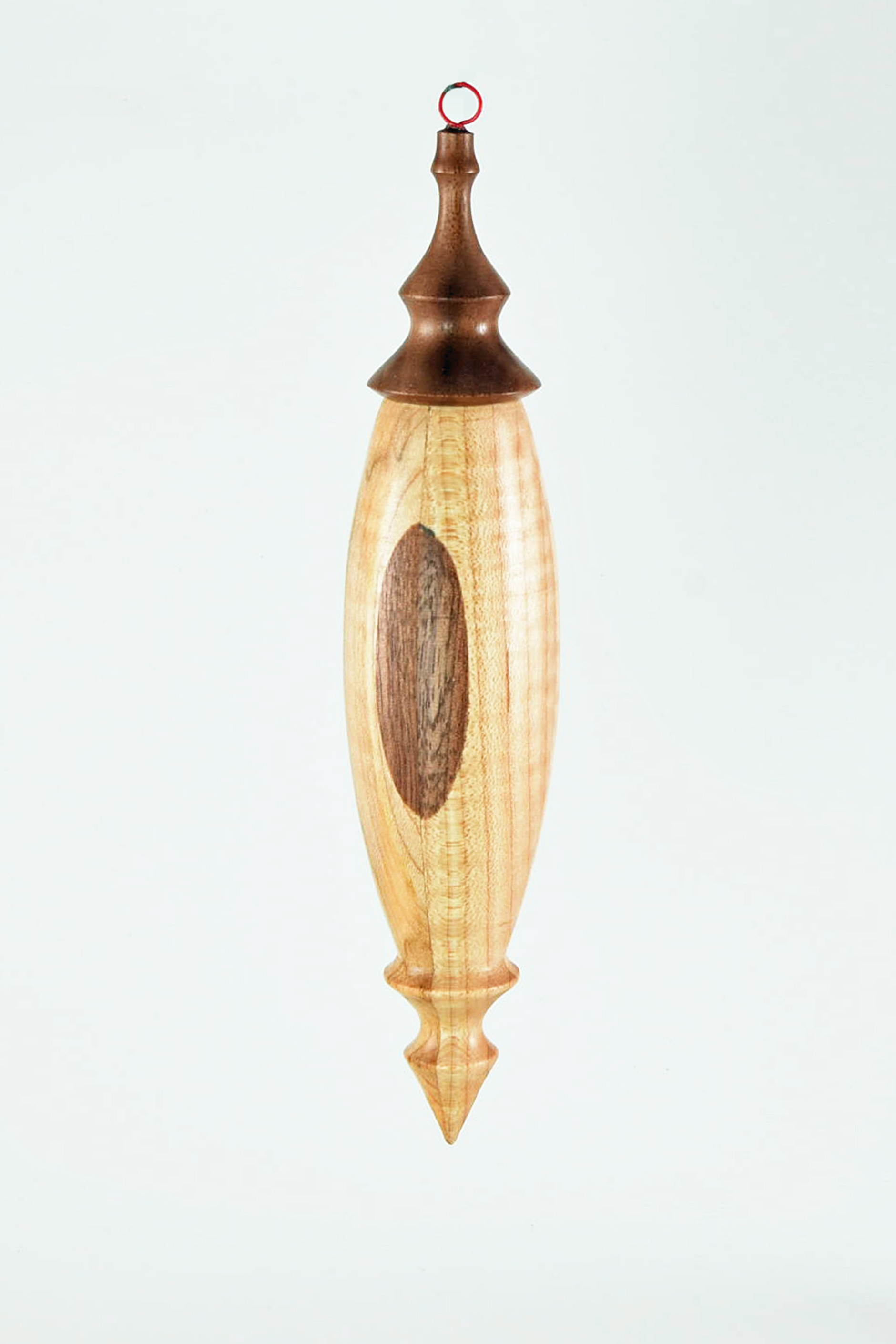 This was supposed to be an inside outside turning -4 pieces of maple with walnut on one edge of each intended to have 2 opposite pieces rotated 90 degrees. Well, they were accidently glued together with the walnut on the outside. So I hollowed it out with a 3/4" bore then turned the shape. It has a walnut finial on top with a wire loop glued in. -Ron Durr