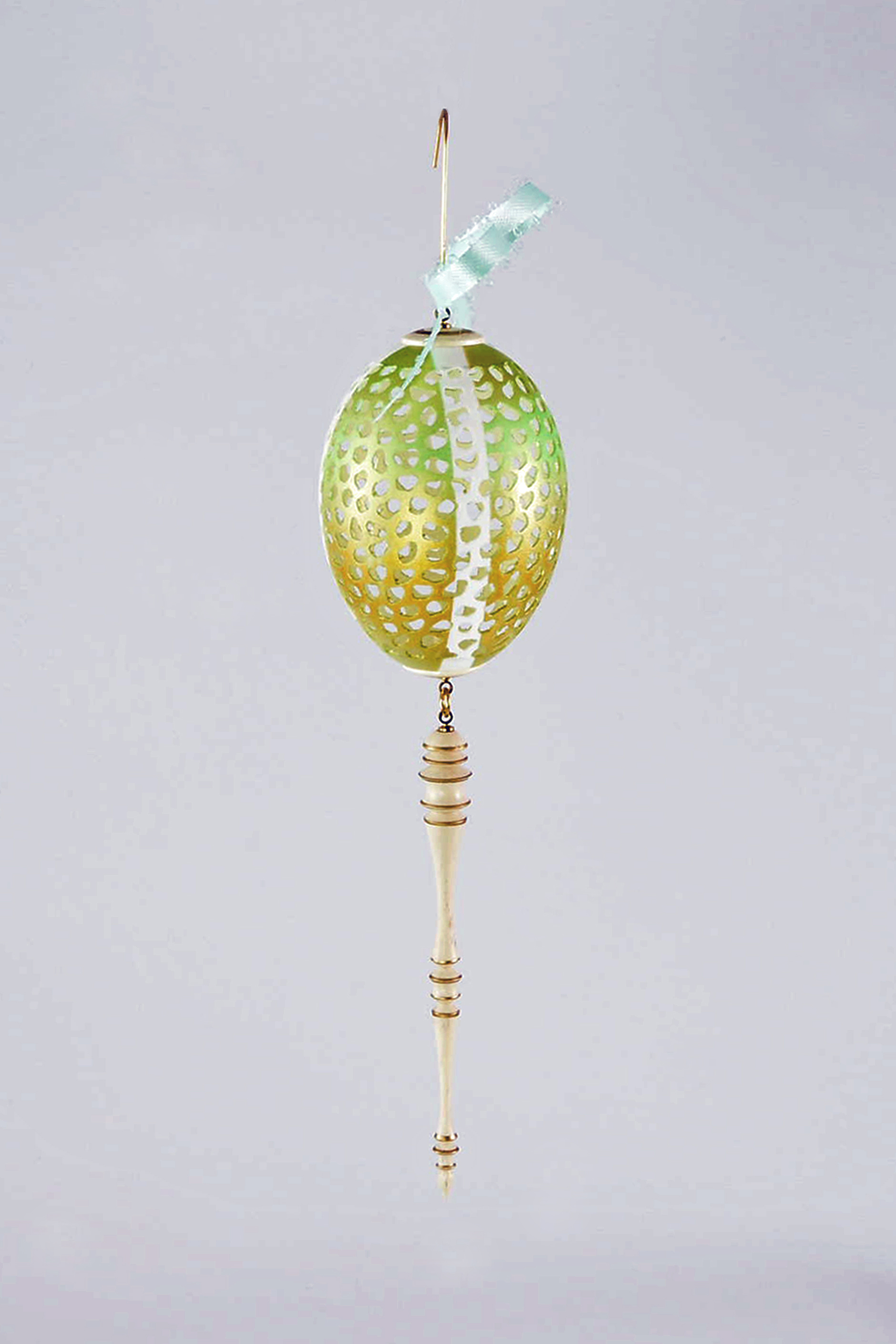 This is a pierced medium-sized duck eggshell. I masked off quadrants and airbrushed it with green pain and gold highlights. It has a Holly cap and icicle with gold paint pen accents. It is one of eight ornaments, all with different designs and color combinations. -Tom Gall